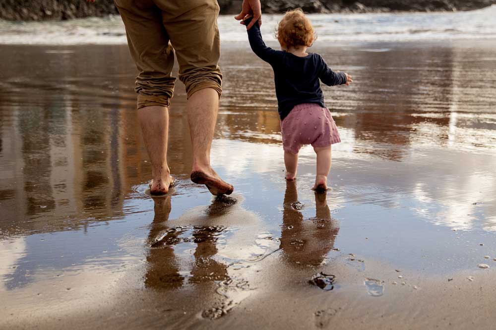 father and daughter walking on beach